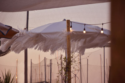 Low angle view of illuminated lighting equipment hanging by building against sky