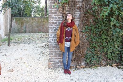 Portrait of a young woman standing against plants