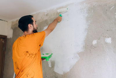 Rear view of man painting wall