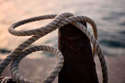 Close-up of rope on rusty metal against sea