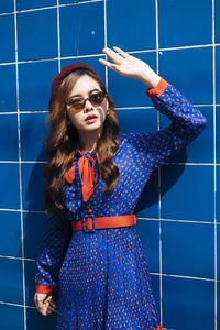 Young woman standing against blue wall