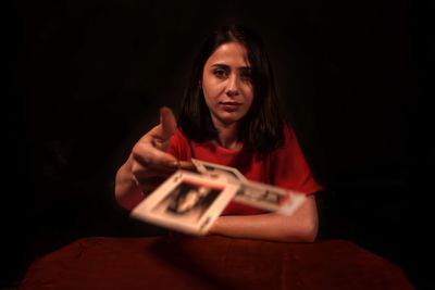 Portrait of woman holding playing cards against black background