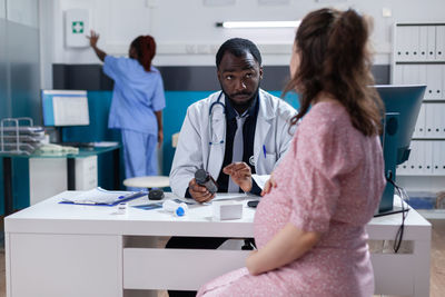 Doctor discussing with pregnant woman at hospital