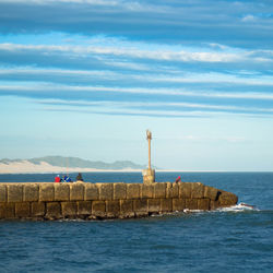 Lighthouse by sea against sky