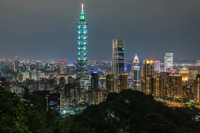 Illuminated cityscape against sky at night