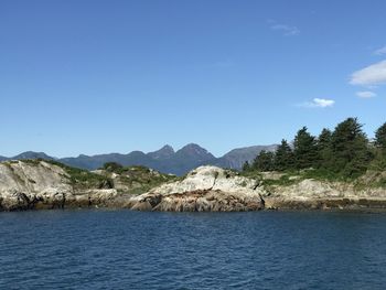 Scenic view of sea and mountains against clear blue sky