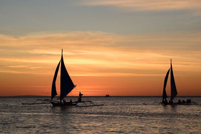 Silhouette sailboat sailing on sea against sky during sunset