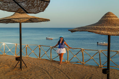 Woman standing on beach by sea against sky