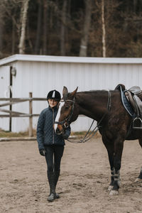 Smiling girl standing with horse and looking at camera