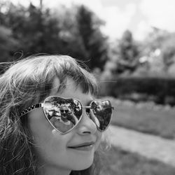 Close-up of cute girl wearing heart shape sunglasses outdoors