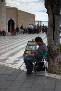 Man sitting on street in city