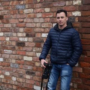 Portrait of young man standing against brick wall