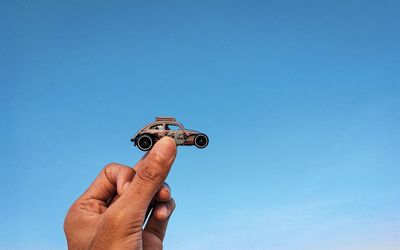 Low angle view of person hand against blue sky