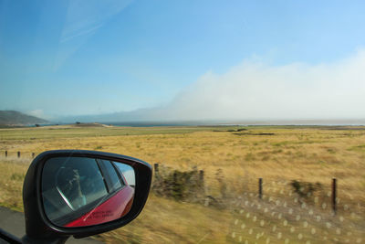 Reflection of car in side-view mirror at landscape