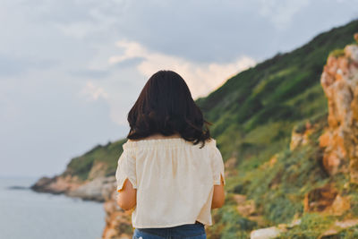 Rear view of woman looking at mountains against sky