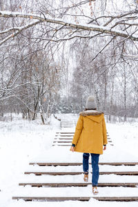 Rear view of woman walking on snow covered field