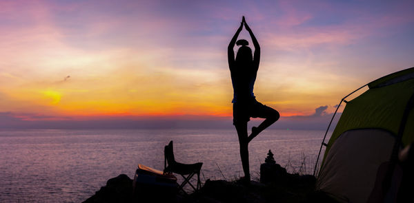 Silhouette person by sea against sky during sunset