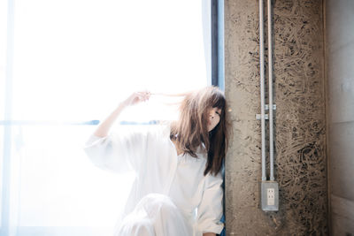 Young woman standing against white wall