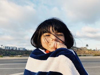 Close-up portrait of girl standing against sky