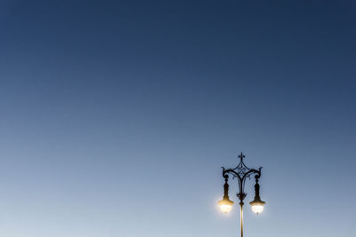 Low angle view of illuminated gas light against clear blue sky