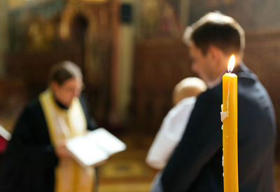 Close-up of lit candle with people in background at church