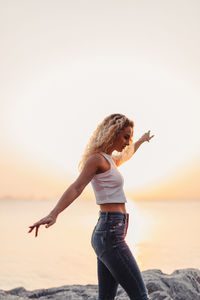 Woman standing on beach against sky during sunset