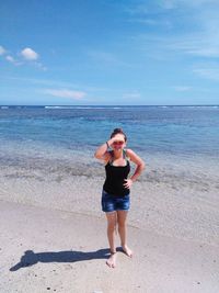 Full length of woman standing on shore at beach against sky during summer