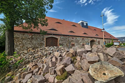 Stone wall of building and trees against sky