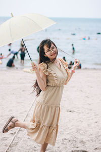 Young woman using phone while standing on beach