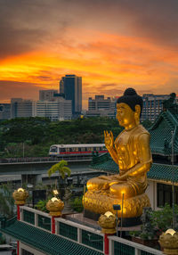 Rear view of man standing against buildings during sunset