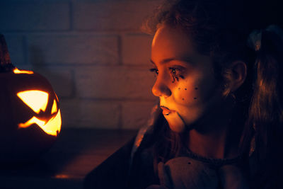 Cute girl wearing costume standing by pumpkin during halloween