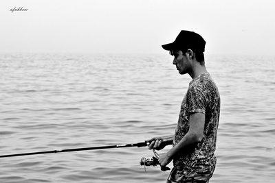 Side view of man standing in sea against sky