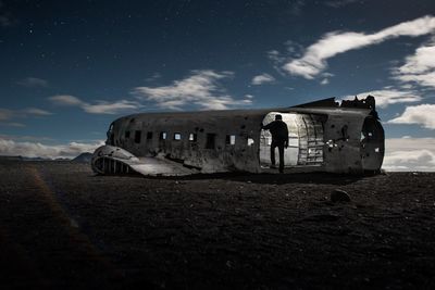 Man standing in abandoned airplane against sky