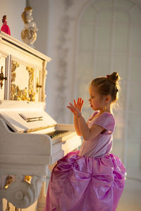 Beautiful girl playing piano in beautiful dress