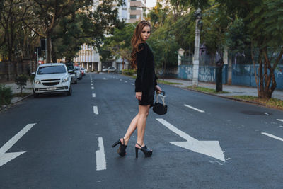 Woman with umbrella on road in city