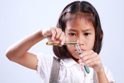 Schoolgirl performing scientific experiment against blue background