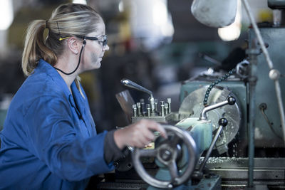 Woman operating machine in workshop