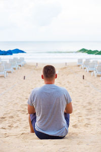 Rear view of man sitting on beach