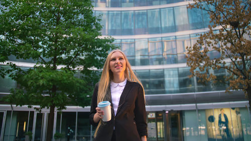 Portrait of young woman standing against trees