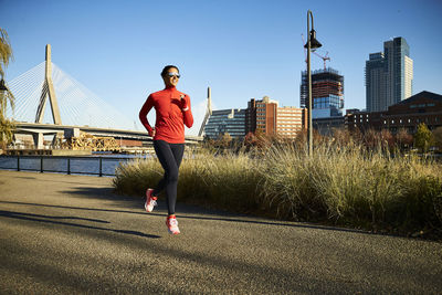 A fit woman runs past the boston skyline.