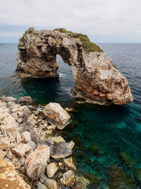 Rock formation in sea against sky