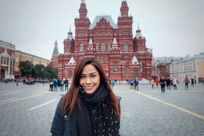 Portrait of smiling woman standing at red square in city