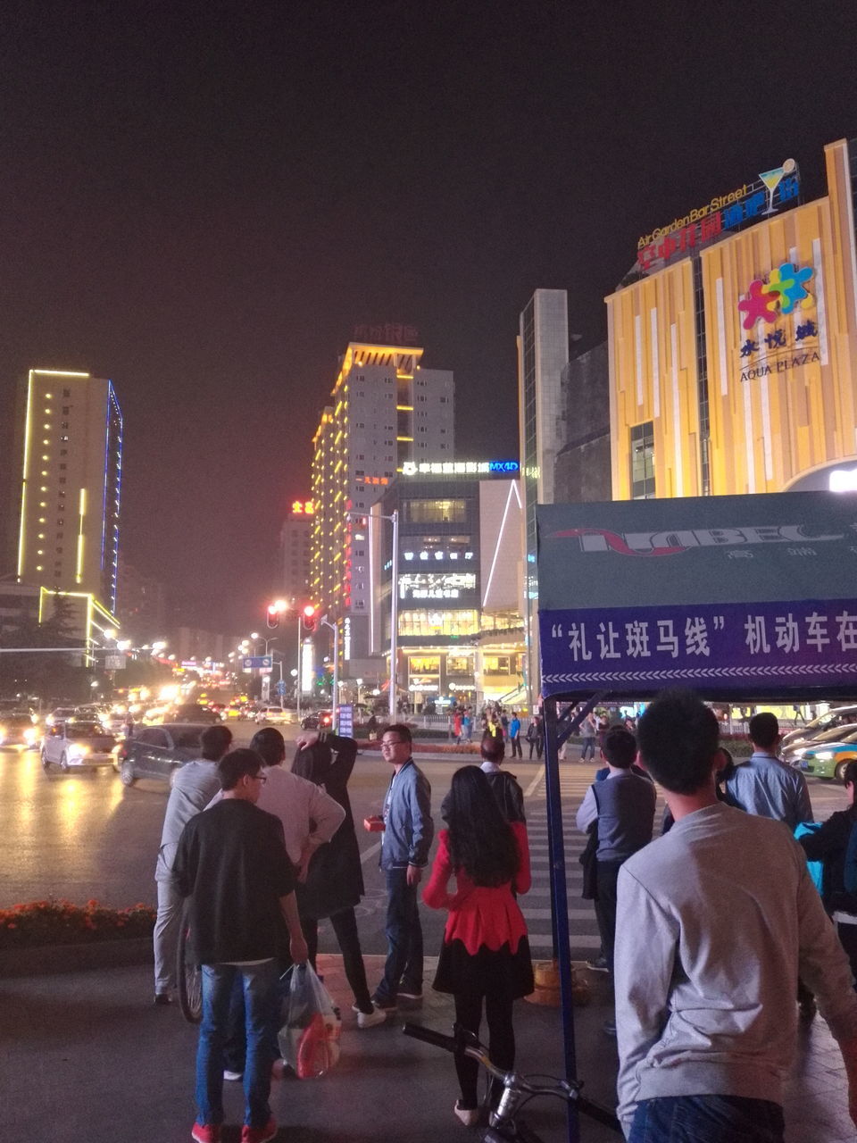 city, men, building exterior, architecture, built structure, street, lifestyles, city life, illuminated, person, night, large group of people, leisure activity, walking, rear view, city street, communication, casual clothing, full length