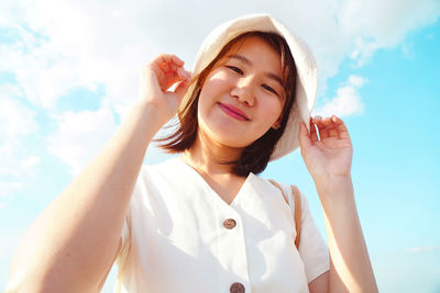 Portrait of smiling young woman against sky