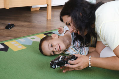 Disabled boy playing toy cars with mother at home. cerebral palsy child entertaining on the mat with