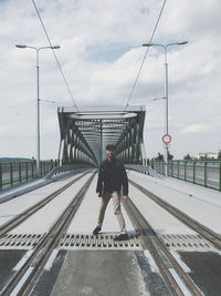 Man standing on bridge against sky