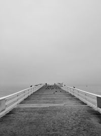 View of footbridge over sea against sky