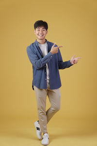 Portrait of smiling boy standing against yellow background