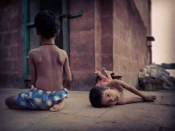 Shirtless boys playing on footpath against house