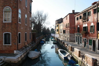 Boats in canal amidst buildings in city